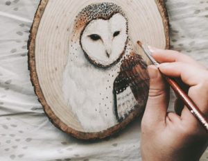 Художник рисует на древесине животных